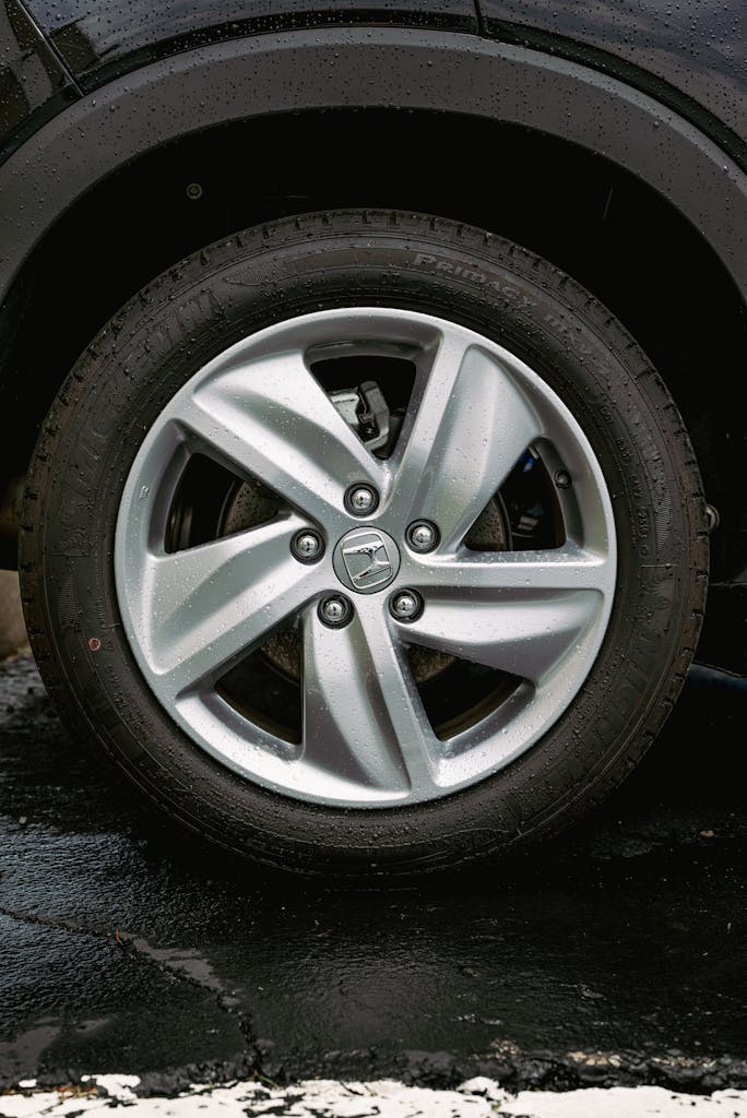 Detailed image of a wet Honda car wheel featuring alloy rim and tire.